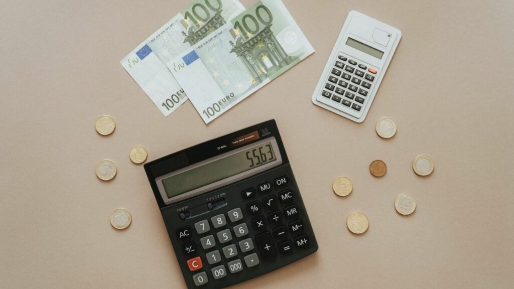 Mesa con calculadoras, billetes y monedas.