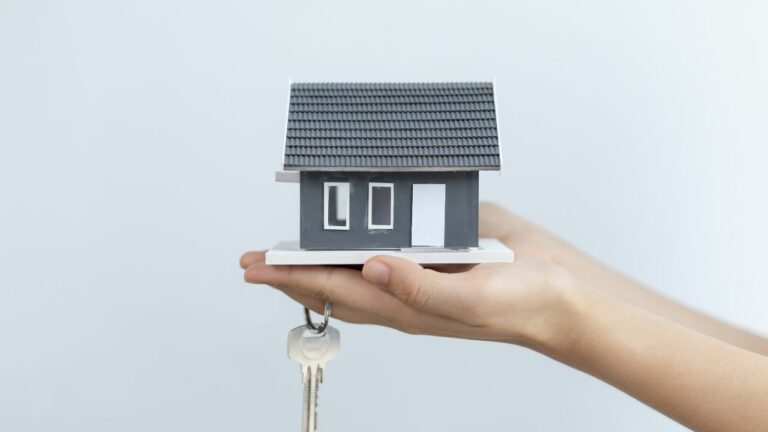 Una mano que sostiene una casa y una llave, para comunicar la idea sobre la propiedad privada.