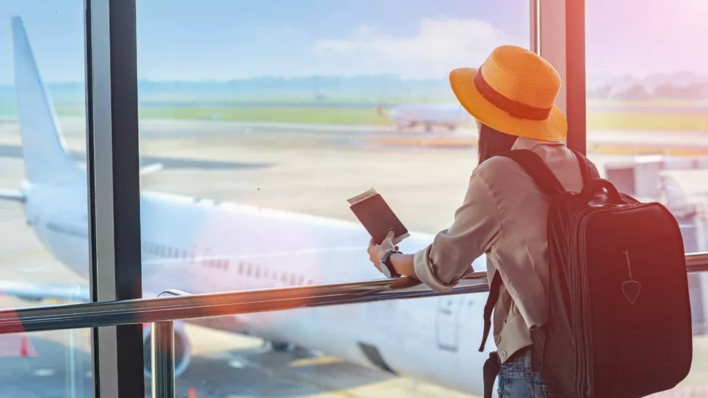 Mujer en un aeropuerto junto con su pasaporte y mochila, para iniciar sus vacaciones coordinada con un agente de viajes.