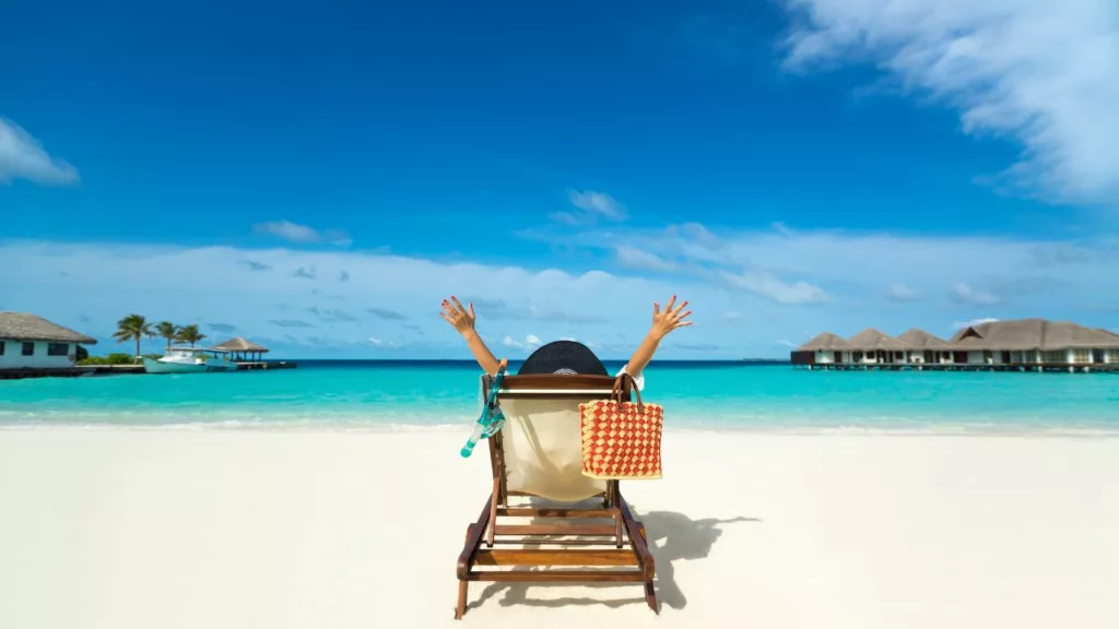 Persona feliz por haber contratada los servicios de un agente de viaje, para disfrutar sentado frente a la playa.