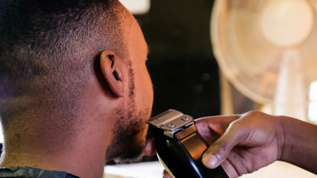 Barbero usa una herramienta para afeitar la barba de su cliente.