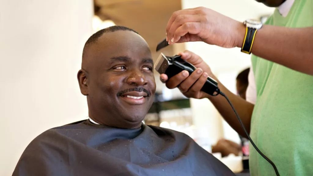 Cliente sonriendo en una barbería junto a su barbero.