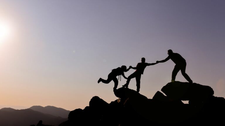 Hombres escalando una montaña y aplicando la división de trabajo en equipo.
