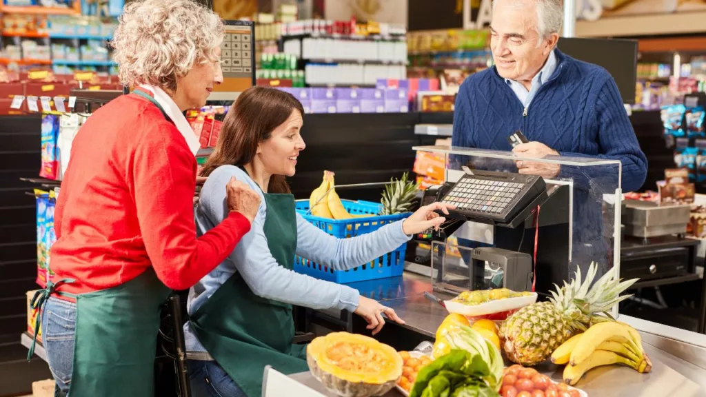 Cajera facturando frutas y vegetales a un cliente de un supermercado.