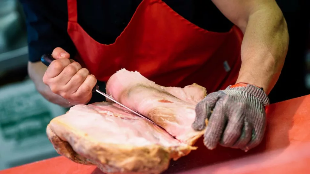 Carnicero profesional cortando carne con un cuchillo.