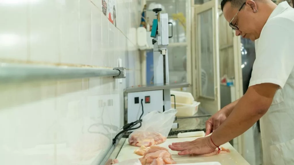 Carnicero cortando partes de carne para venderse y consumirse.