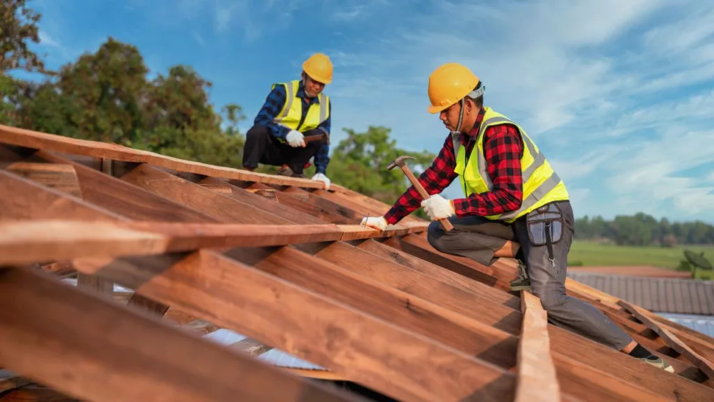 Dos carpinteros construyendo el techo de una casa con madera.