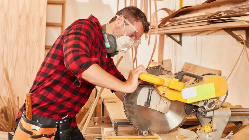 Personal de carpintería cortando madera con una sierra industrial.