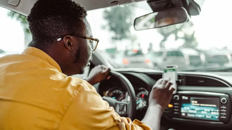 Chófer de uber visualizando el GPS de su celular, para llevar a su pasajero a su destino.