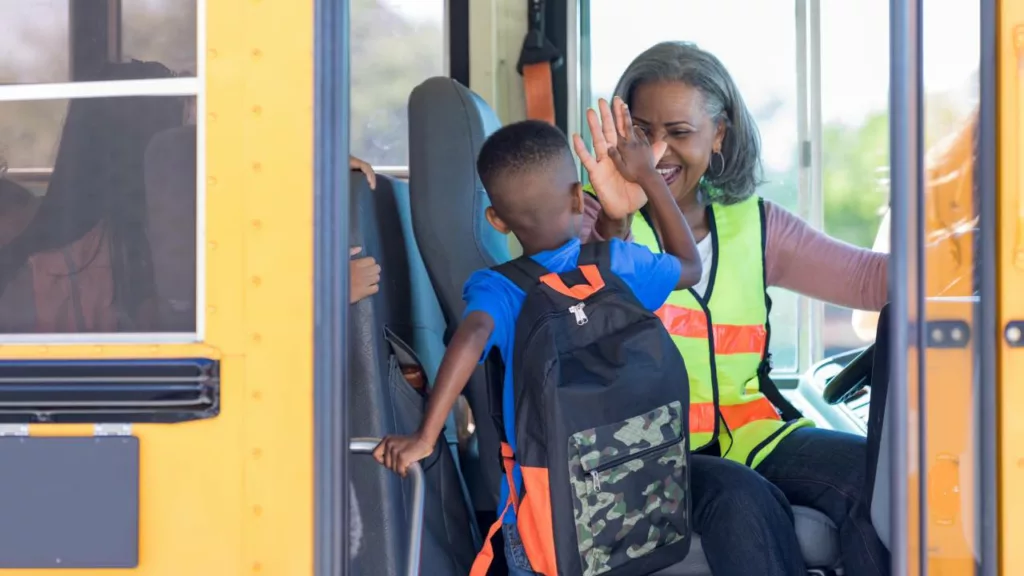 Chófer de bus escolar, recibiendo un niño que irá a la escuela a estudiar.