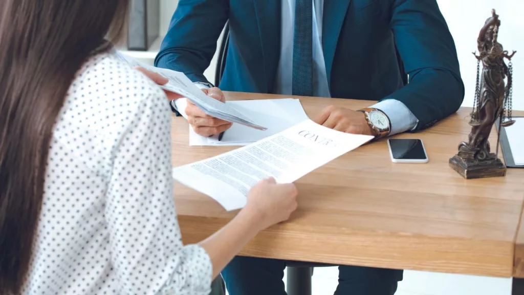 Cliente le muestra documentos de contractos a un abogado.