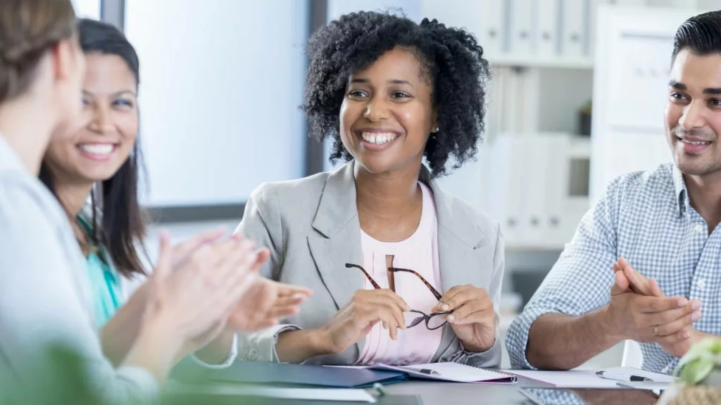 Administradora sonriendo y con una vestimenta formal en una reunión de negocios.