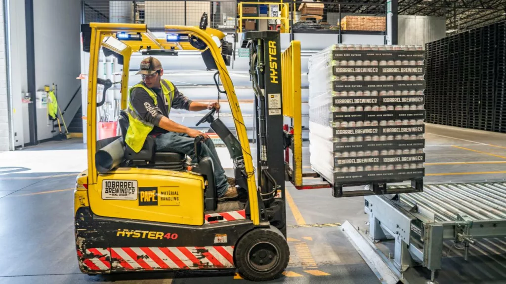 Personal de almacén trasladando productos de inventario con un carro de carga.
