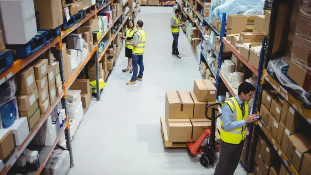 Almacenistas colaborando en un pasillo, para organizar el inventario del almacén.