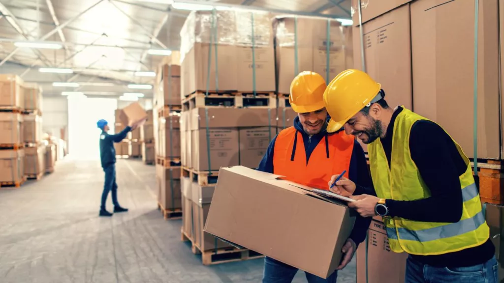 Tres almacenistas trabajando en equipo en una empresa de logística.