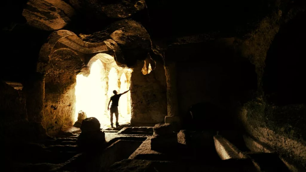 Antropólogo en una cueva, estudiando alguna pieza histórica.