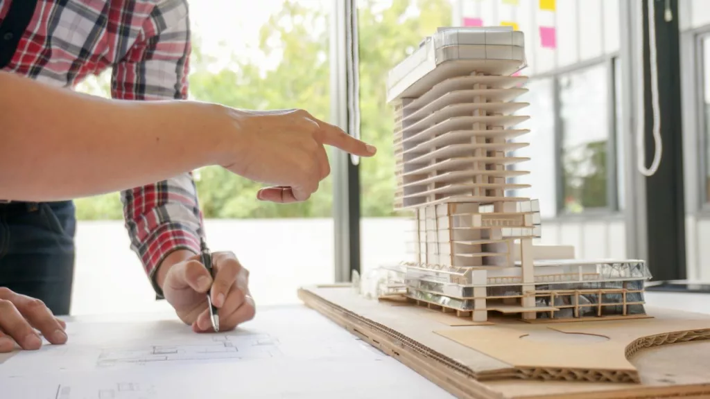 Arquitectos con una maqueta de un edificio, para explorar mejoras de los planos.