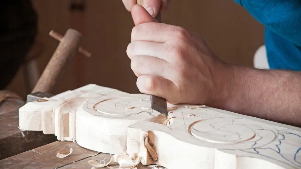 Hombre trabajando con una madera, para crear un producto de artesanía.