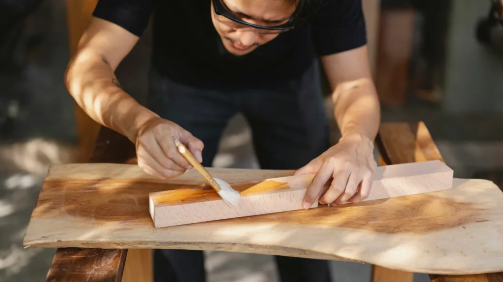 Artesano pintando una madera para crear un producto.