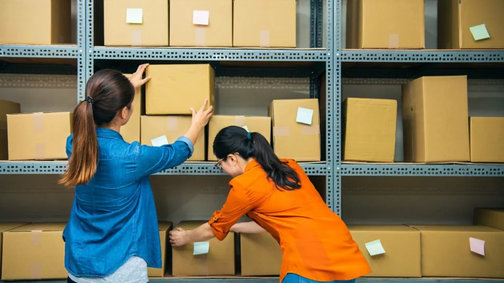 Dos mujeres trabajando juntas con unas cajas, para asistirse una con otras.
