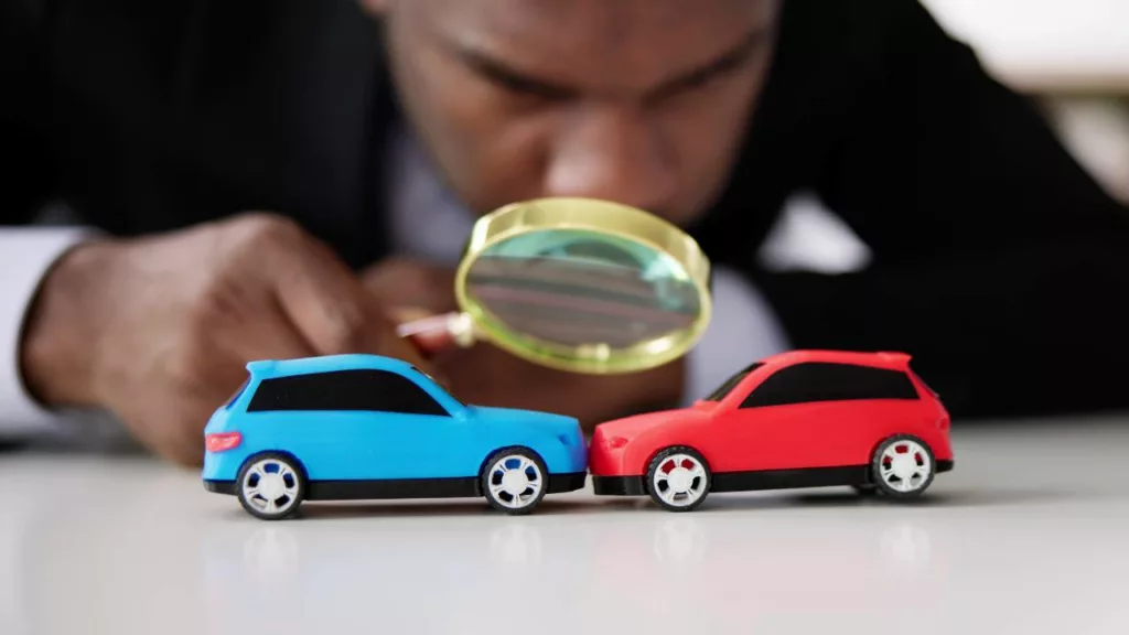 Agente de seguros evaluando con una lupa, si no hubo un accidente fraudulento, para el reclamo de la póliza de seguro de vehículos.