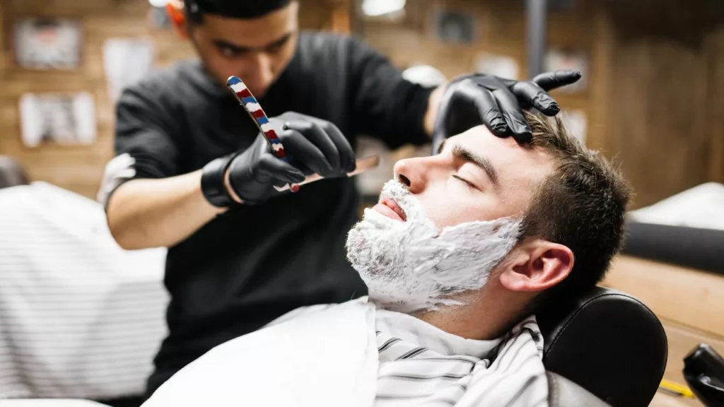 Barbero afeitando la barba de un cliente.