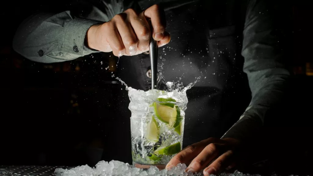 Bartender mezclando una bebida con trozos de limón.