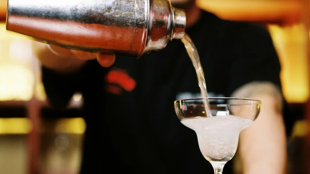 Bartender sirviendo una bebida en una copa.