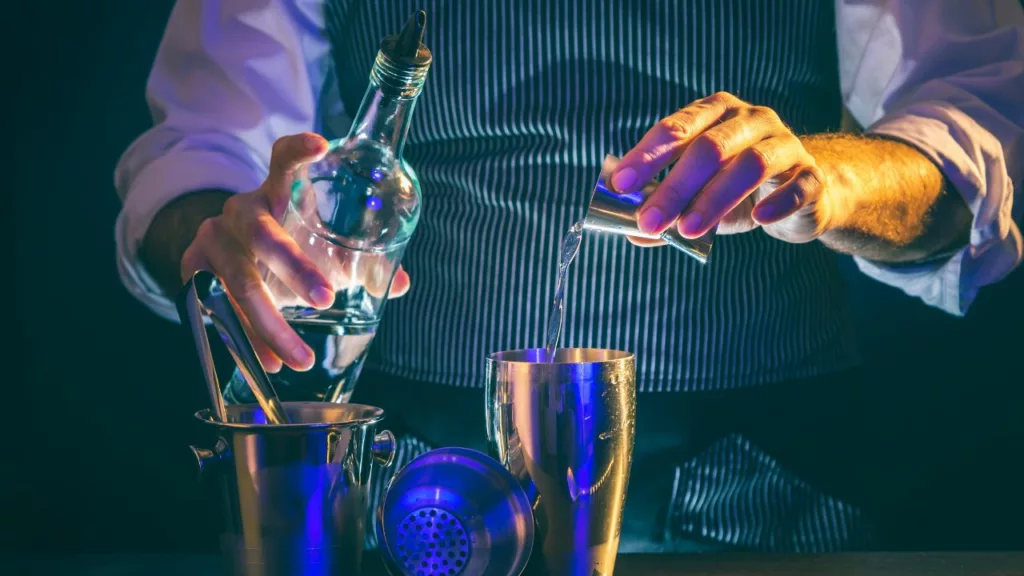 Bartender vestido con ropa elegante preparando una bebida.