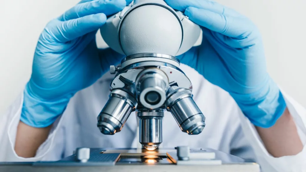 Bioanalista usando un microscopio para analizar muestras.