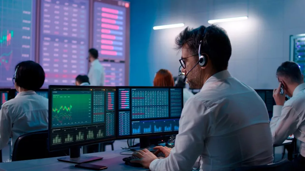 Corredor de bolsa de valores trabajando desde su computadora de 2 pantallas, para revisar gráficos del mercado.