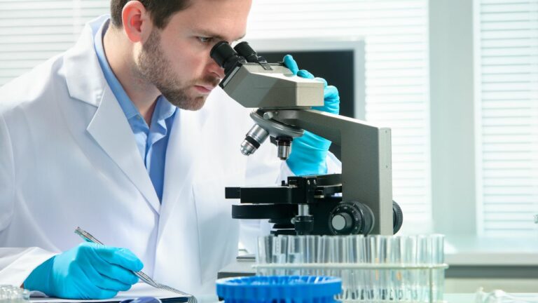 Bioanalista usando un microscopio para examinar pruebas biológicas.