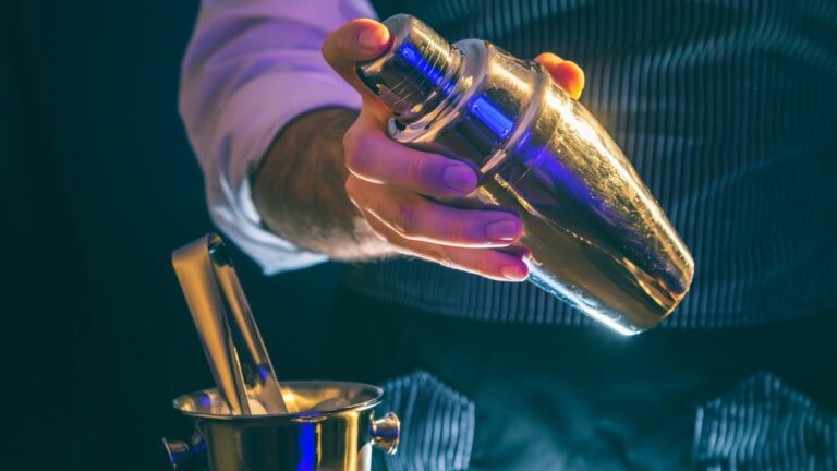 Bartender, con ropa elegante, preparando una bebida en un evento.