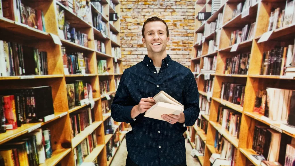 Bibliotecario sosteniendo un libro y sonriendo.