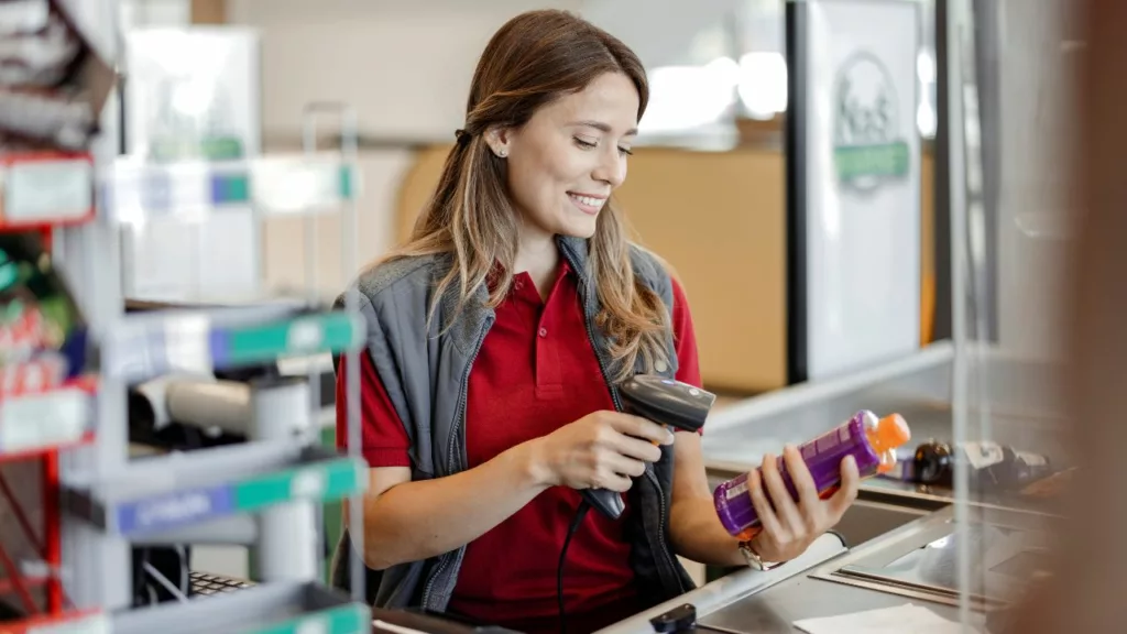 Mujer trabajando en caja y facturando un producto.