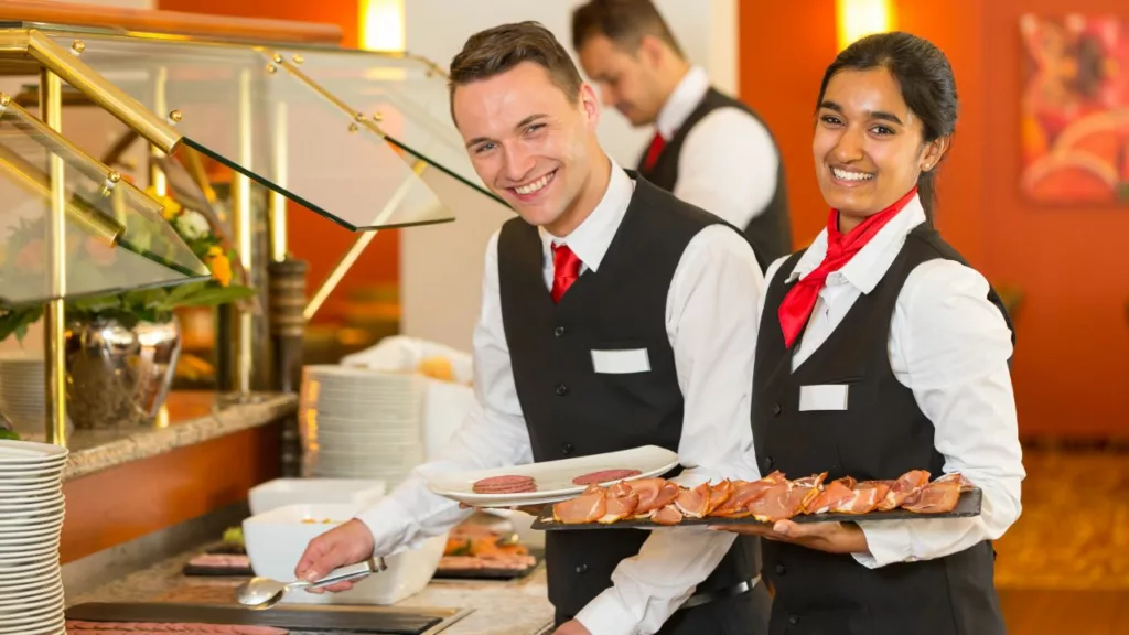 Dos camareros y una camarera trabajando en buffet.