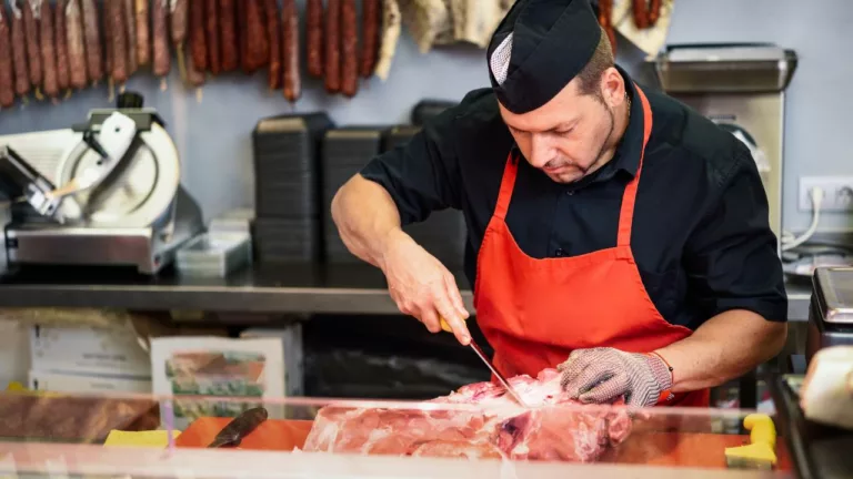 Carnicero cortando carne para vender a sus clientes.