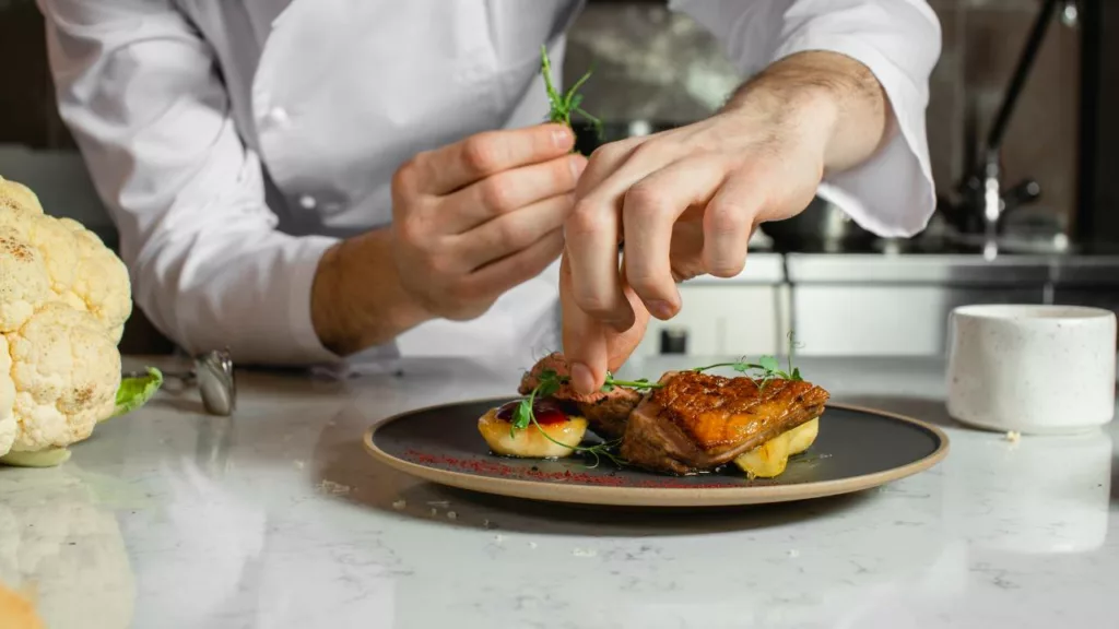 Chef usando técnicas de arte culinario en la comida.