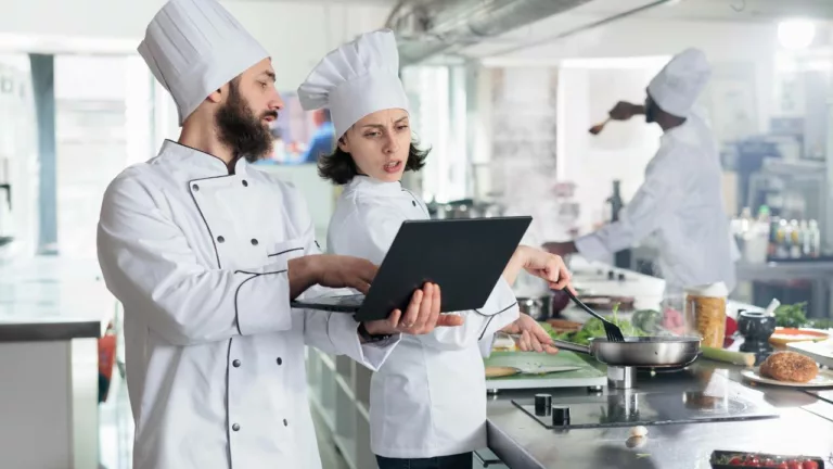 Dos chefs coordinando platos en la cocina de un restaurante para trabajar.